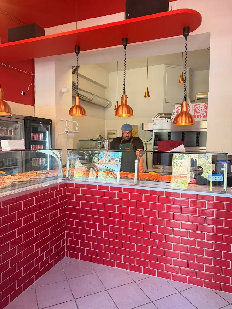 Bancone rosso e vetrina delle pizze di Mano Pizza