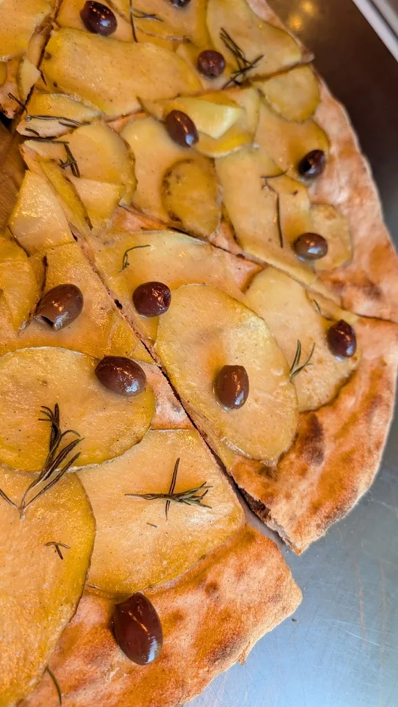 Pizza con patate, olive e rosmarino tagliata a spicchi
